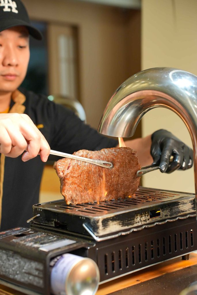 Chef searing a block of A5 wagyu on the tabletop grill