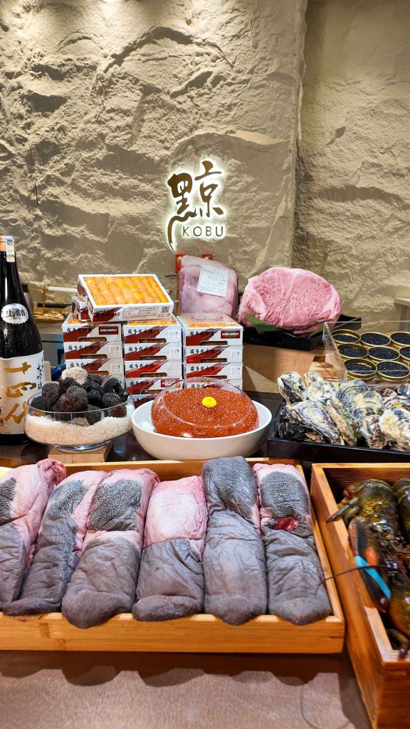 The ingredient counter at KOBU, beneath the 黥 mark on the stone wall